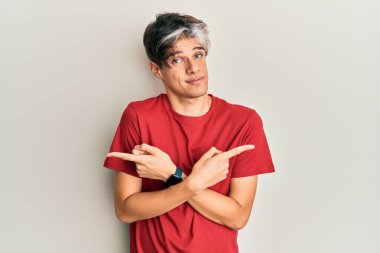 Gündelik kıyafetler giyen genç İspanyol adam her iki tarafı da parmaklarıyla işaret ediyor, farklı yönlerde farklı görüşler. 