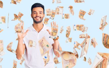 Genç, yakışıklı, gündelik kıyafetler giyen, kendini beğenmiş ve mutlu bir şekilde gülümseyen, on numarayı gösteren İspanyol bir adam..