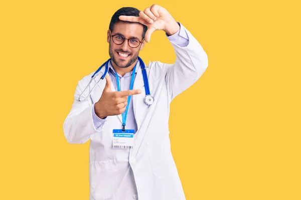 医者の制服を着た若いヒスパニック系の男と幸せな顔で手や指でフレームを作る笑顔聴診器 創造性と写真の概念 — ストック写真