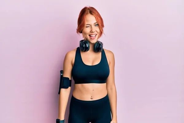 Ung Vacker Rödhårig Kvinna Gympakläder Och Med Hörlurar Blinkande Tittar — Stockfoto