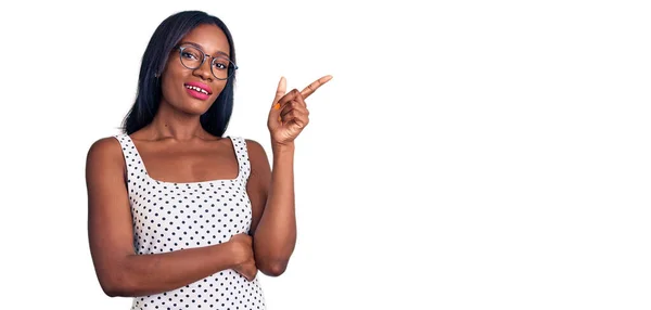 Молодая Африканская Американка Повседневной Одежде Очках Улыбается Показывая Рукой Пальцем — стоковое фото