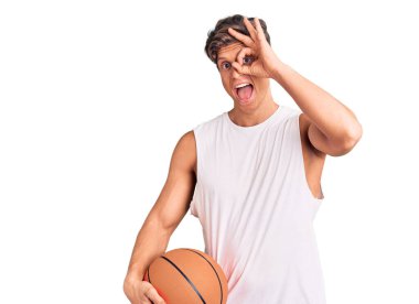 Basketbol topu tutan yakışıklı genç adam gülümsüyor. Mutluluktan gülümsüyor. 