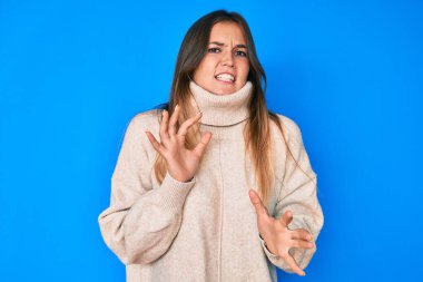 Tüylü, kışlık kazak giyen güzel beyaz kadın tiksindirici tepki verdiği için tiksinmiş ve ürkek bir ifade takındı. Eller havada. 