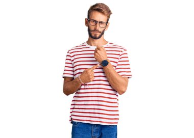 Sakallı, sıradan kıyafetler ve gözlük takan yakışıklı sarışın adam. Saati, sabırsızlığı ve rahat bir ifadeyle kameraya bakıyor. 