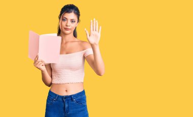 Genç ve güzel bir kadın kitabı açık elle tutuyor. Dur işareti yapıyor. Ciddi ve kendinden emin bir ifadeyle. 