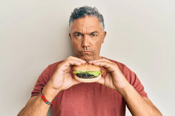 Όμορφος Μεσήλικας Ώριμος Άνθρωπος Τρώει Ένα Νόστιμο Κλασικό Burger Σκεπτικιστής — Φωτογραφία Αρχείου