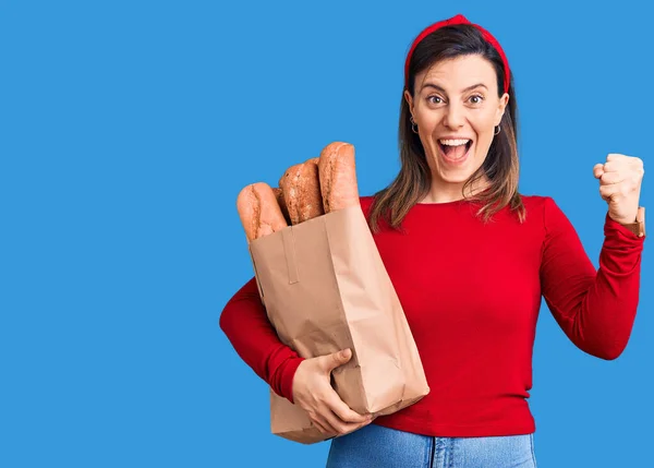 Joven Mujer Hermosa Sosteniendo Bolsa Papel Con Pan Gritando Orgulloso — Foto de Stock