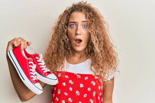 Beautiful Caucasian Teenager Girl Holding Red Casual Shoes Scared Amazed — Stock Photo, Image