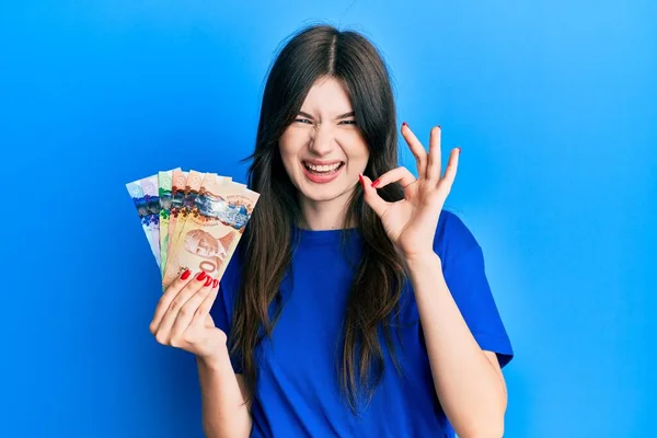Młoda Piękne Kaukaskie Dziewczyna Gospodarstwa Kanadyjskie Dolary Robi Znak Palcami — Zdjęcie stockowe