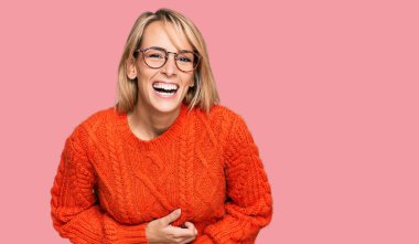 Güzel sarışın kadın, günlük kıyafetler ve gözlük takıyor, gülümsüyor ve kahkahalar atıyor.. 