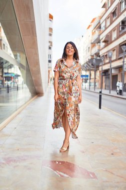 Güzel, genç bir kadın, şık kıyafetler giyip sokakta yürüyor.