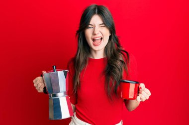 İtalyan kahvesi içen genç beyaz kız kameraya seksi bir ifadeyle bakıyor, neşeli ve mutlu bir yüzle.. 