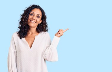 Orta yaşlı, güzel bir kadın. Günlük süveter giyiyor. Yüzünde kocaman bir gülümseme var.. 