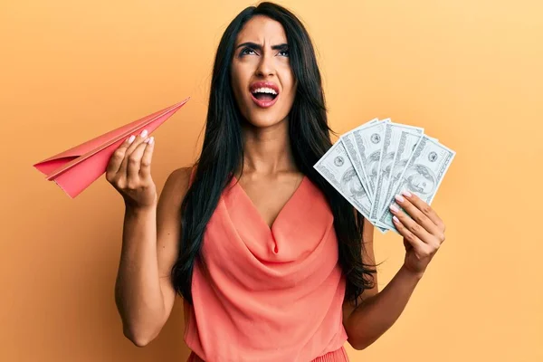 Beautiful Hispanic Woman Holding Paper Plane Dollars Angry Mad Screaming — Stock Photo, Image