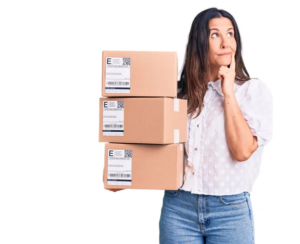 Young Beautiful Brunette Woman Holding Delivery Cardboard Package Serious Face — Stock Photo, Image