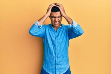 Genç Arap adam gündelik kıyafetler giyip baş ağrısı çekiyor. Acı ve migren yüzünden çaresiz ve stresli. Eller başının üstünde.. 