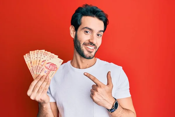 Ung Latinamerikan Man Håller Mexikanska Pesos Leende Glad Pekar Med — Stockfoto