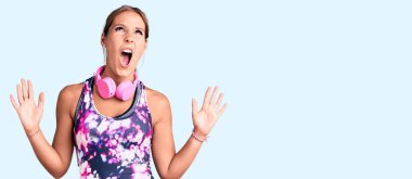 Spor kıyafetleri giyen, kulaklık takan, deli gibi bağıran, agresif ifade ve kollarıyla bağıran genç ve güzel İspanyol bir kadın. hüsran kavramı. 