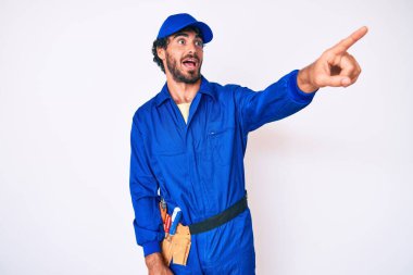 Kıvırcık saçlı ve ayı gibi giyinen yakışıklı genç adam. Parmakla işaret ediyor. Şaşkın şaşkın, ağzı açık, önde bir şey. 