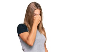 Sıradan kıyafetler giyen genç sarışın kadın yorgun burnu ve gözleri ovuşturup yorgun ve baş ağrısı çekiyor. Stres ve hüsran kavramı. 