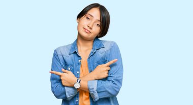 Kısa saçlı, sıradan kot ceketli, iki tarafı da parmaklarıyla gösteren genç ve güzel İspanyol kadın farklı yönlere bakıyor. 