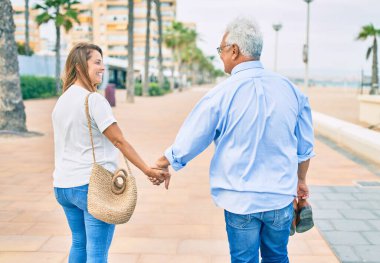 Orta yaşlı İspanyol çift gülümseyerek gezinti güvertesinde mutlu mesut yürüyor.