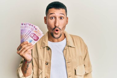 Dövmeleri olan yakışıklı bir adam 50 Meksika pezosu tutuyor. Korkmuş ve şaşırmış bir şekilde ağzı açık, inançsız bir yüz. 