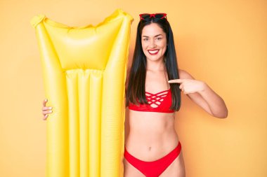 Bikini giyen güzel beyaz bir kadın elinde yüzen birini işaret ederek mutlu ve gururlu bir şekilde gülümsedi. 