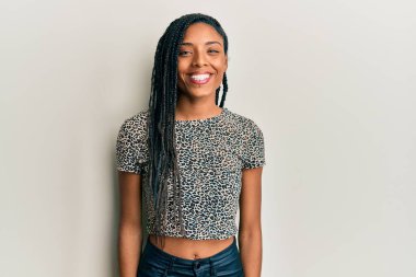 Yüzünde mutlu ve havalı bir gülümseme olan gündelik kıyafetler giyen Afro-Amerikalı bir kadın. şanslı kişi. 