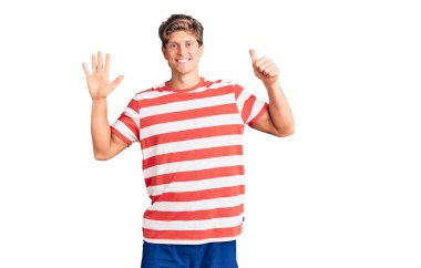 Genç ve yakışıklı bir adam gündelik giysiler giyer ve altı numaralı parmaklarını göstererek gülümserken kendinden emin ve mutlu olur.. 