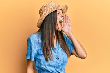 Genç İspanyol kadın yaz şapkası takıyor, bağırıyor ve ağızdan ağıza bağırıyor. iletişim konsepti. 
