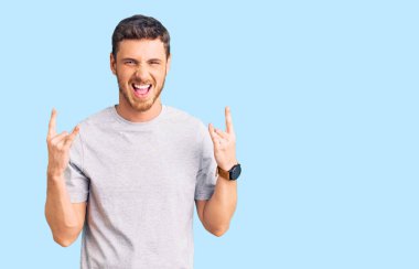 Ayılı yakışıklı genç adam gündelik tişört giyip çılgın bir ifadeyle bağırıyor elleri havada rock sembolü yapıyor. Müzik yıldızı. ağır kavram. 