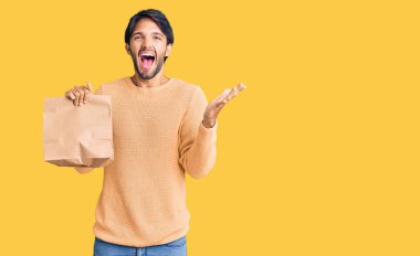 Yakışıklı İspanyol adam elinde paket kağıdı ile zaferi mutlu bir gülümsemeyle kutluyor ve kazanan el kaldırıyor. 