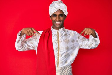 Gelenek giyinmiş yakışıklı Hintli adam Sherwani sari giysileri giyiyor. Kendine güvenen, yüzünde gülümseme olan, kendini gururlu ve mutlu gösteren.. 