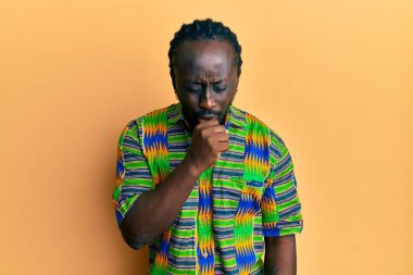 Renkli etnik kıyafetler giyen yakışıklı genç bir adam kendini kötü hissediyor ve soğuk algınlığı veya bronşitin belirtisi olarak öksürüyor. sağlık hizmeti kavramı. 