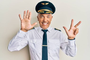 Yakışıklı, olgun, uçak pilotu üniforması giyen, 8 numaralı parmaklarıyla işaret eden, kendinden emin ve mutlu gülümseyen bir adam.. 