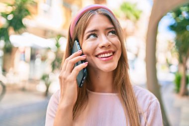 Beyaz kız gülümsüyor. Şehirdeki akıllı telefondan konuşuyor..