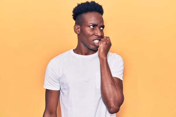 穿着休闲服的年轻的非洲裔美国人看上去很紧张 双手放在咬指甲的嘴上 焦虑问题 — 图库照片