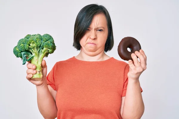 Donna Bruna Con Sindrome Con Broccoli Ciambella Cioccolato Scettico Nervoso — Foto Stock