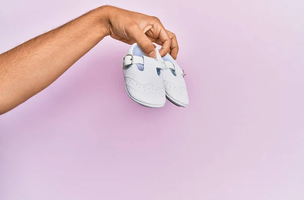 Main Hispanique Tenant Des Chaussures Bébé Sur Fond Rose Isolé — Photo