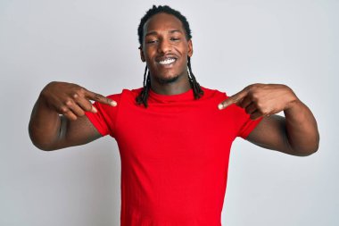 Saçları örgülü, kendine güvenen, gülümseyen, kendini gururlu ve mutlu gösteren Afro-Amerikan bir adam.. 