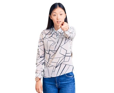 Gayri resmi tişört giyen genç ve güzel bir Çinli kadın kameraya kızgın ve sinirli bir şekilde seni işaret ediyor. 