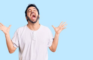 Gündelik kıyafetler giyen genç İspanyol adam başarı için deli ve çılgınlığı kutluyor kollarını kaldırmış ve gözlerini kapatmış heyecanla bağırıyor. Kazanan konsept 