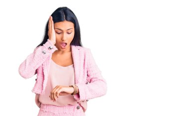 İş kıyafetleri giymiş genç ve güzel bir Latin kız saate bakıyor. Endişeli, geç kalmaktan korkuyor. 