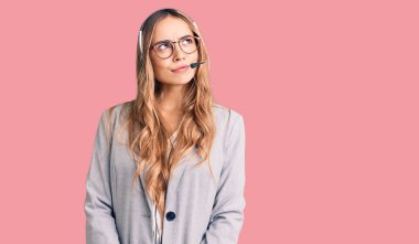 Çağrı merkezi kulaklığı takan genç, güzel, sarışın bir kadın. Gülümsüyor ve başka tarafa bakıyor.. 