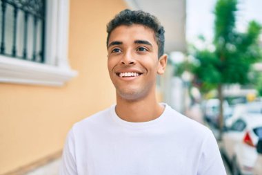 Genç Latin adam gülümseyerek şehirde mutlu mesut yürüyor..