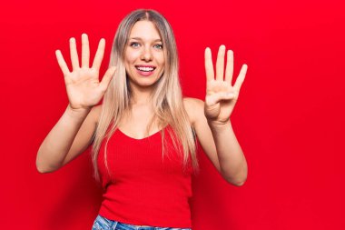 Gündelik kıyafetler giyen genç sarışın kadın dokuz numarayı gösterip işaret ederken kendinden emin ve mutlu bir şekilde gülümsüyor.. 