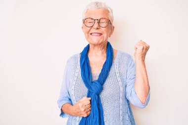 Mavi gözlü, gri saçlı, sıradan süveter ve eşarp giyen son sınıf güzeli bir kadın. Kolları havada ve gözleri kapalı bir şekilde başarıyı kutluyor ve şaşırıyor. 