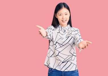 Genç, güzel, Çinli bir kadın, günlük tişört giyiyor, gülümsüyor, yardım eli uzatıyor ve kabul ediyor.. 