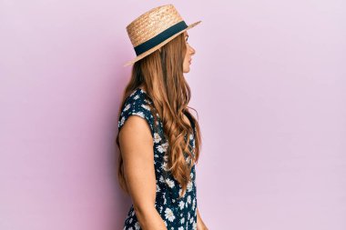 Yazlık şapka takan genç esmer kadın, rahat profil pozu veriyor, kendine güvenen bir gülümsemesi var.. 